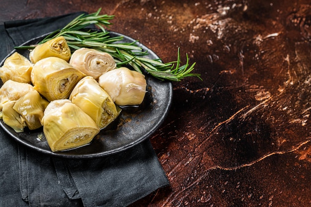 Italian appetizer Artichoke hearts pickled in olive oil with herbs and spices Dark background Top view Copy space