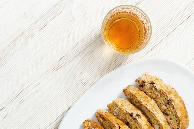 Italian biscotti cookies in white plate and sweet wine Vin Santo.