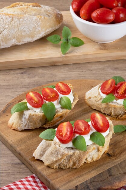 Italian bruschetta with roasted tomato, cheese cream, basil and herbs, selective focus.