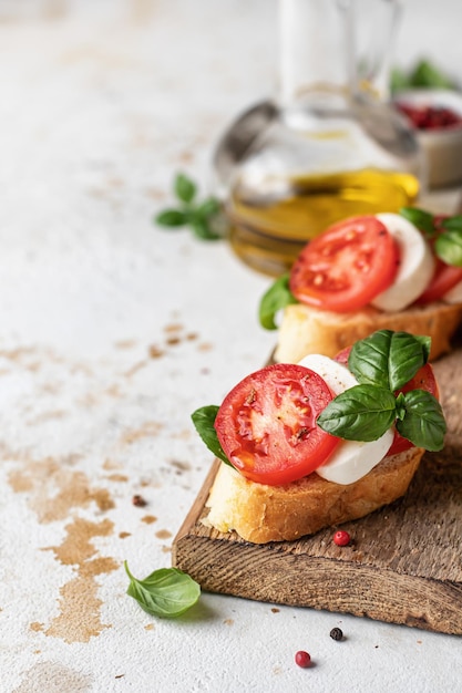 Bruschetta italiana con pomodori, mozzarella e basilico su tavola di legno rustica con ingredienti copia spazio