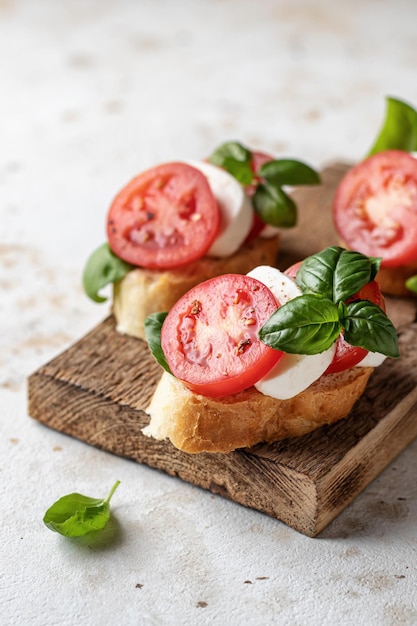 Italian bruschetta with tomatoes mozzarella and basil on rustic wooden board