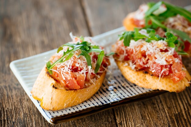 Italian bruschetta with tomatoes parmesan arugula