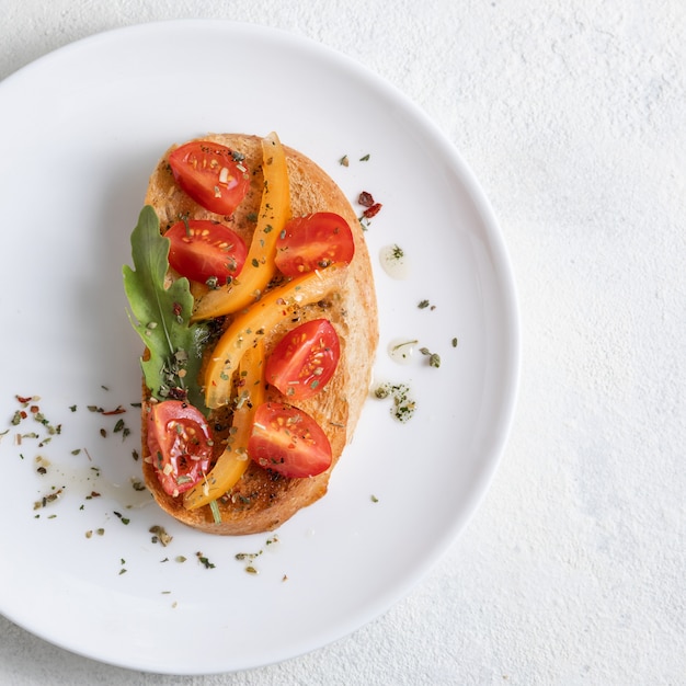 Foto bruschetta italiana con i pomodori su un piatto bianco contro fondo bianco. vista dall'alto