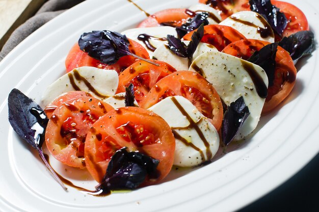 Insalata caprese italiana. ingredienti mozzarella, pomodori, basilico, sale, pepe, balsamico.