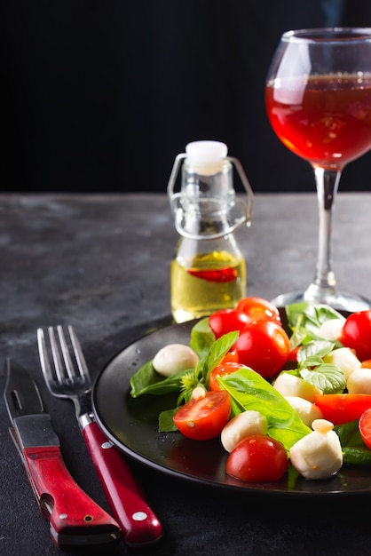 Italian Caprese salad with red wine, tomatoes, fresh organic mozzarella and basil on stone table