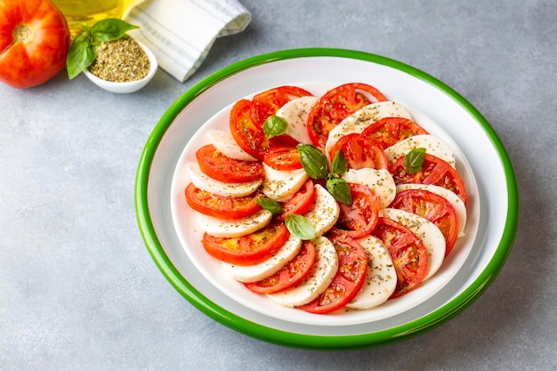 Italian caprese salad with sliced tomatoes, mozzarella, basil, olive oil