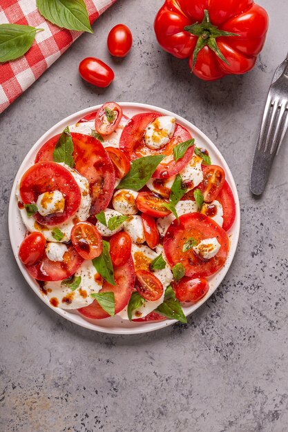 Italian caprese salad with sliced tomatoes, mozzarella cheese, basil, olive oil, balsamic vinegar. Top view, copy space.