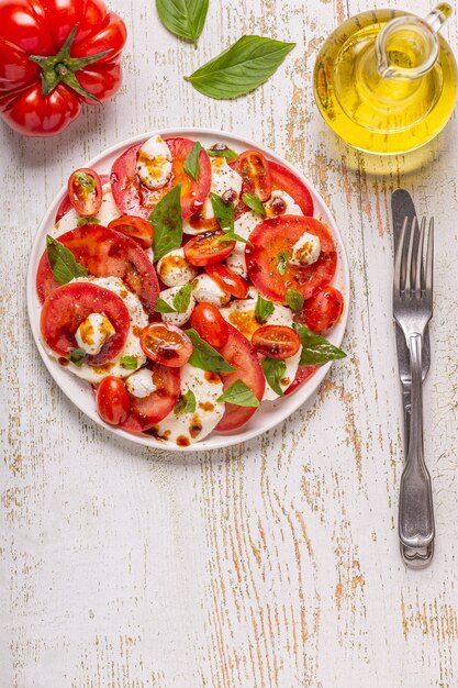 Italian caprese salad with sliced tomatoes, mozzarella cheese, basil, olive oil, balsamic vinegar. Top view, copy space.