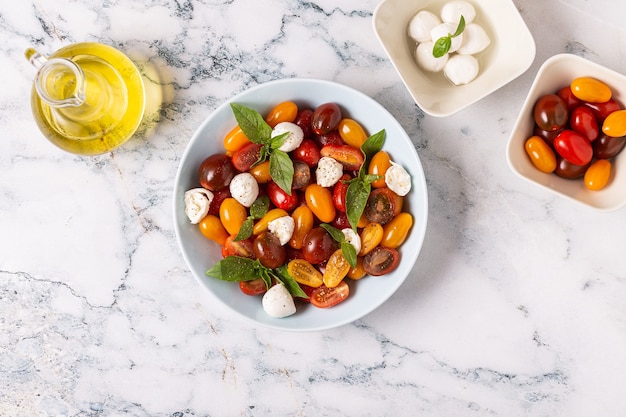 Italian caprese salad with tomatoes, mozzarella cheese, basil, olive oil, top view.