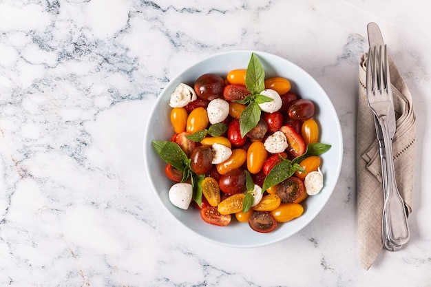 Italian caprese salad with tomatoes, mozzarella cheese, basil, olive oil, top view.