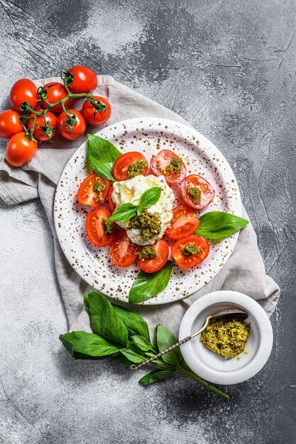 Italian cheese stracciatella on small plate served with fresh tomatoes and basil.