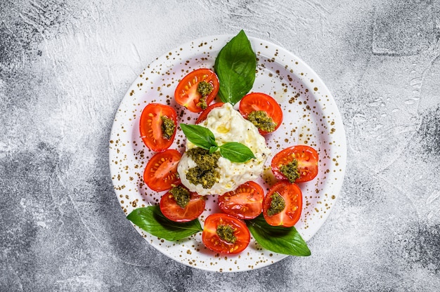 Italian cheese stracciatella on small plate served with fresh tomatoes and basil.