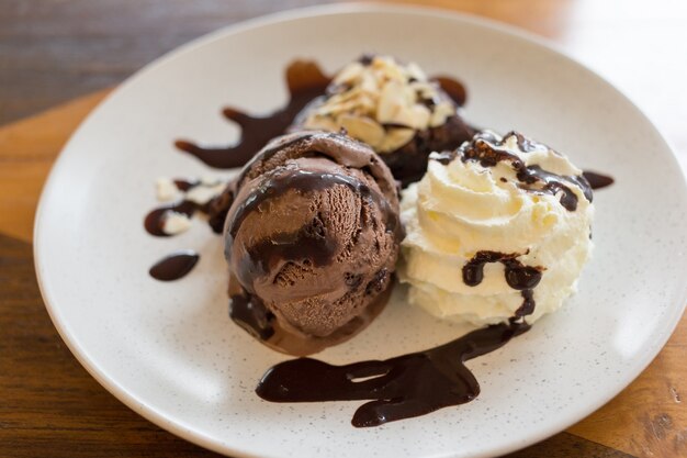 ブラウニーとホイップクリームのイタリアンチョコレートアイスクリームに白いプレートにチョコレートをトッピング。