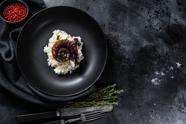 Italian classic Risotto with octopus tentacles. Black background