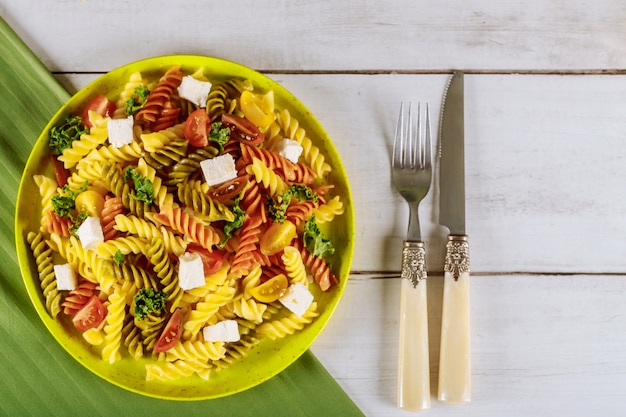 Foto rotini italiani variopinti della pasta con i pomodori ciliegia su superficie di legno bianca