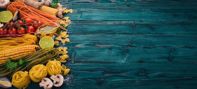 イタリア料理新鮮な野菜パスタヌードルスパゲッティのセット青い木製の背景に上面図コピースペース