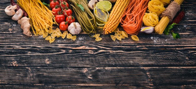 イタリア料理新鮮な野菜とスパイスパスタヌードルスパゲッティのセット暗い木製の背景に上面図コピースペース