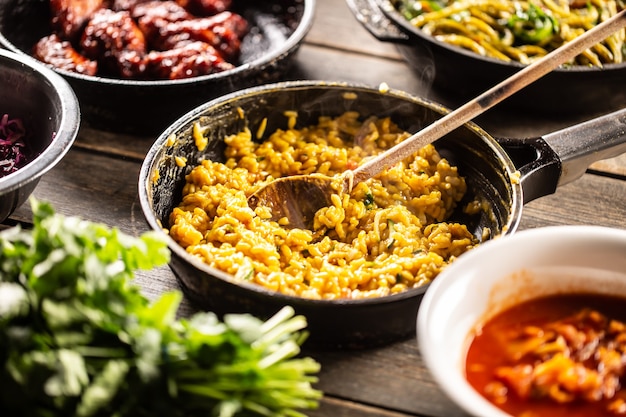 Risotto cremoso italiano con zafferano, curcuma o butternut in padella con un cucchiaio di legno.