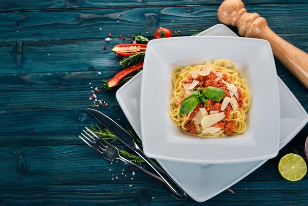 Italian cuisine pasta with tomatoes and parmesan cheese On a wooden background Top view Copy space