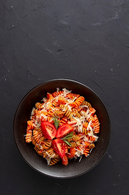 Italian dish made of colored fusilli pasta in tomato sauce with parmesan cheese and spices top view