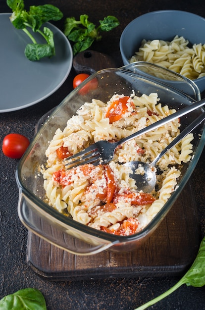 Italian dish of  pasta mixing with Feta cheese baked and tomatoes on a dark background. Fetapasta. Trending viral recipe, Flat lay, copy space