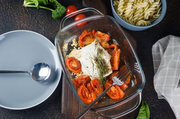 Italian dish of  pasta mixing with Feta cheese baked and tomatoes on a dark background. Fetapasta. Trending viral recipe, Flat lay, copy space