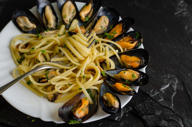 Italian dish with steamed mussels with wine. Close up of spaghetti on a fork. Seafood eating concept. Selective focus.