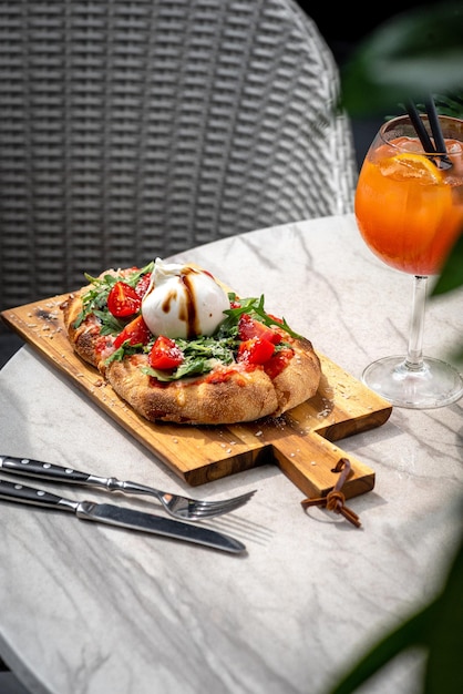 Italian focaccia with burrata and zucchini flower with tomatoes cherry and ham flatlay top view composition on a black background