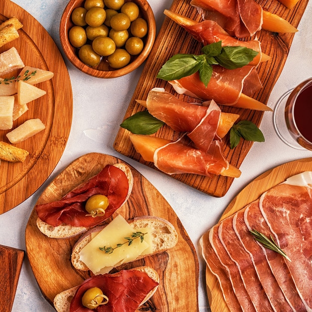 Italian food background with ham, cheese, olives, bread and wine