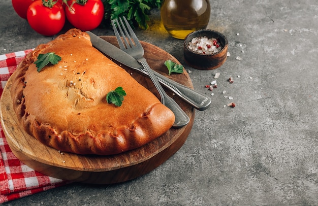 Italian food, closed pizza calzone with cheese, gray stone background.