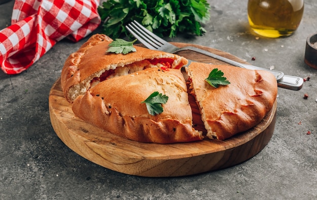 Italian food, closed pizza calzone with cheese, gray stone background.