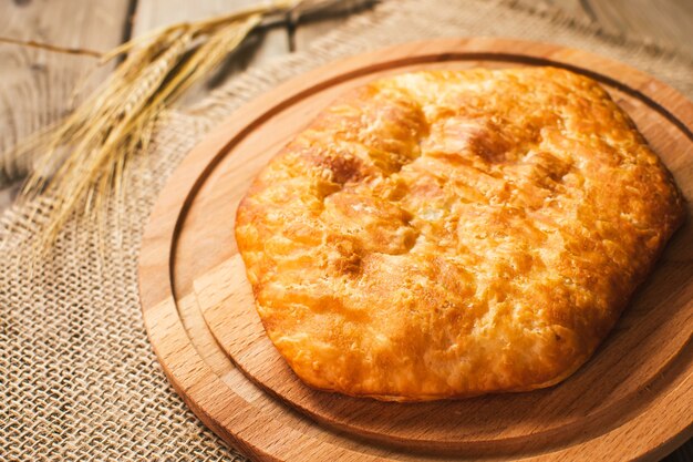 Italian food, closed pizza calzone with Spinach and Cheese, wooden background. Freshly baked