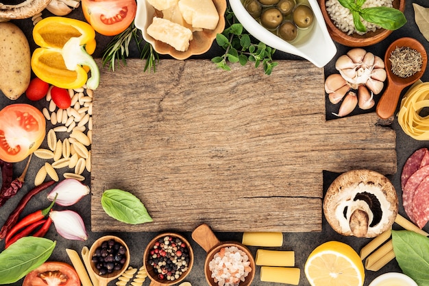 Italian food cooking ingredients on dark stone background with flat lay and copy space.