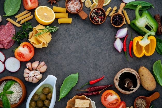 Italian food cooking ingredients on dark stone background .