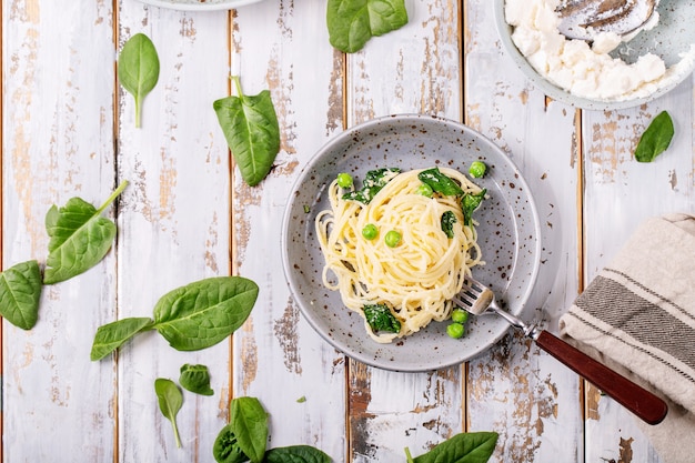 이탈리아 음식 : 신선한 집에서 만든 tagliatelle 채식 달걀 파스타 까르보나라는 흰색 나무 배경 위에 리코 타 치즈와 시금치와 함께 제공됩니다.