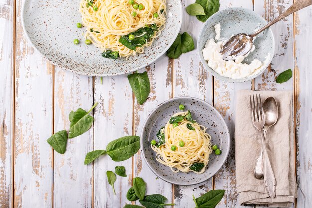 이탈리아 음식 : 신선한 집에서 만든 tagliatelle 채식 달걀 파스타 까르보나라는 흰색 나무 배경 위에 리코 타 치즈와 시금치와 함께 제공됩니다.