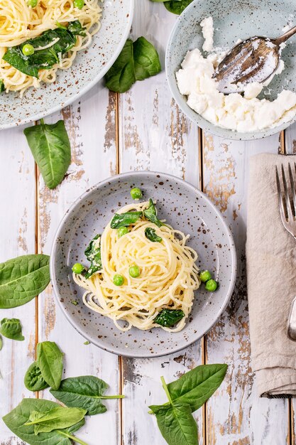 이탈리아 음식 : 신선한 집에서 만든 tagliatelle 채식 달걀 파스타 까르보나라는 흰색 나무 배경 위에 리코 타 치즈와 시금치와 함께 제공됩니다.