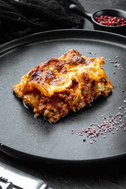 검은 돌 배경에 접시에 이탈리아 음식 뜨겁고 맛있는 갓 구운 라자냐