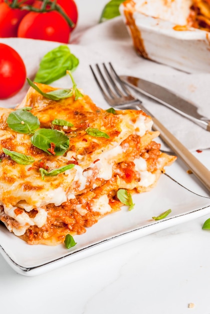 Ricetta del cibo italiano. cena con lasagne classiche alla bolognese con salsa besciamella, parmigiano, basilico e pomodori