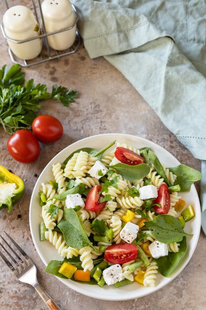 Italian food - salad with gluten free pasta spinach tomatoes beans and feta cheese