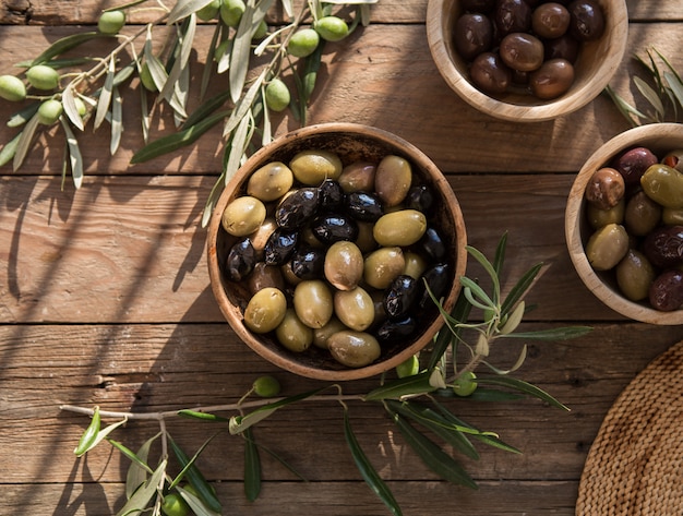 Italian food, with bell peppers and green olives, stuffed with cheese, black olives, olive oil on wooden table