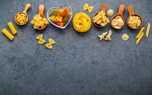 Italian foods concept and menu design. Various kind of pasta on dark stone background with flat lay.