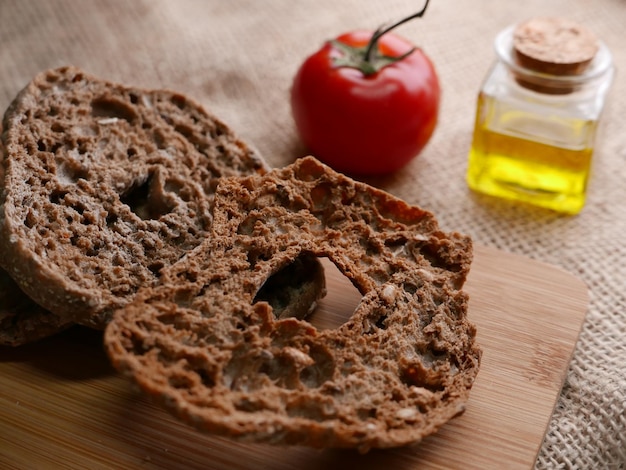 Foto fresella italiana con accanto un pomodoro su un tavolo rustico con un mesale di iuta