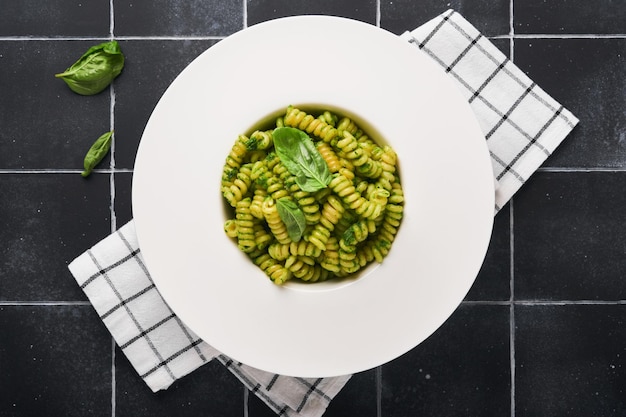 Foto fusilli italiani con pesto fusilli con pesto di basilico ed erbe aromatiche parmigiano basilico e aglio su piatto bianco su sfondo di pietra nera vista dall'alto spazio di copia mock up