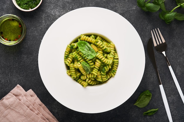 Foto fusilli italiani con pesto fusilli con pesto di basilico ed erbe aromatiche parmigiano basilico e aglio su piatto bianco su sfondo di pietra nera vista dall'alto spazio di copia mock up