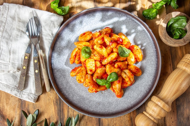 Italian Gnocchi with tomato sauce and basil on wooden background