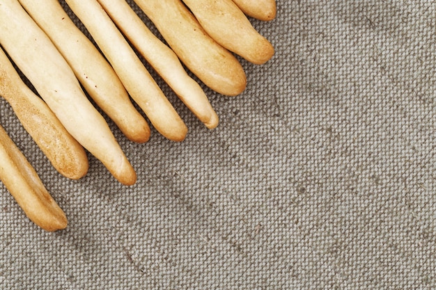 Italian grissini dry breadsticks close up on grey colored tablecloth.