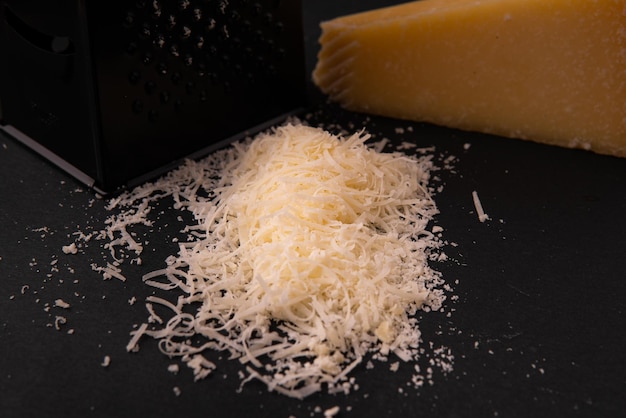 Italian hard Parmesan cheese slice cut grated Black background Top view Copy space