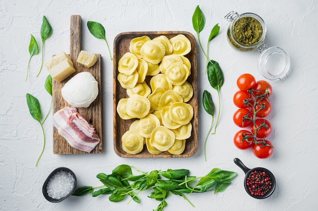 Italian Homemade ravioli with ingredients, ham, basil, pesto, mozzarella set, on wooden tray, top view flat lay