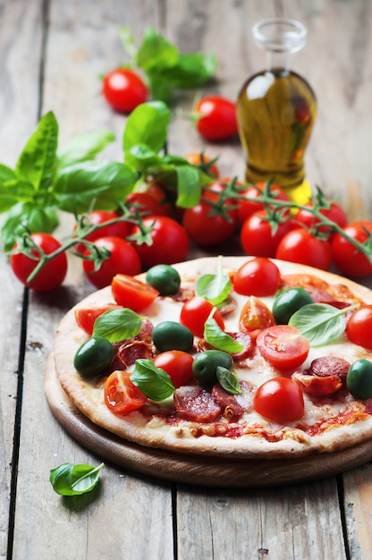 Italian hot pizza with salami, olive and tomato